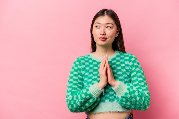 Jovem chinesa isolada em fundo rosa, inventando um plano em mente, criando uma ideia