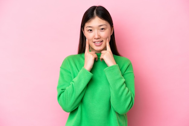 Jovem chinesa isolada em fundo rosa sorrindo com uma expressão feliz e agradável