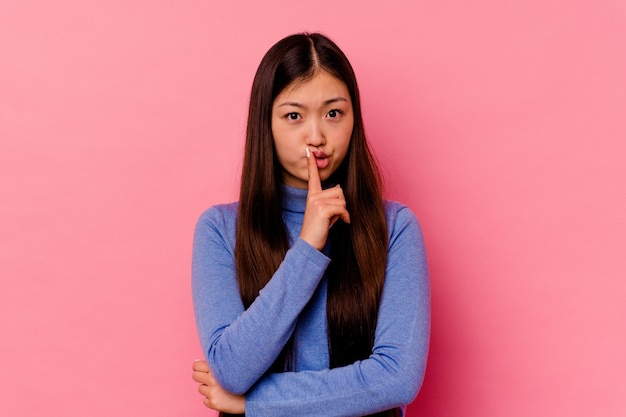 Jovem chinesa isolada na parede rosa olhando infeliz com expressão sarcástica.