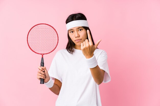 Jovem chinesa jogando badminton em uma rosa apontando com o dedo para você como se estivesse convidando a se aproximar.