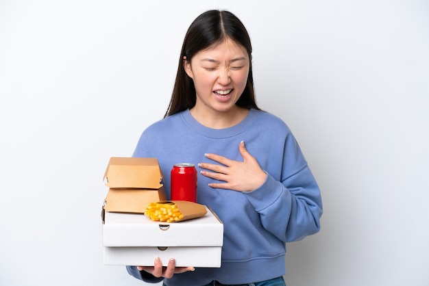 Jovem chinesa segurando fast food isolado no fundo branco sorrindo muito