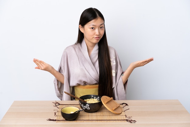 Foto jovem chinesa vestindo quimono e comendo macarrão com dúvidas