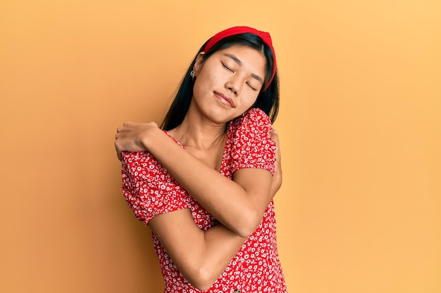 Jovem chinesa vestindo roupas casuais abraçando-se feliz e positiva sorrindo confiante amor próprio e autocuidado