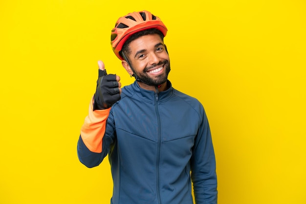 Jovem ciclista brasileiro isolado em fundo amarelo com polegares para cima porque algo bom aconteceu