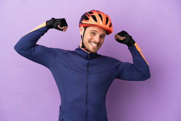 Jovem ciclista brasileiro isolado em um fundo roxo fazendo um gesto forte