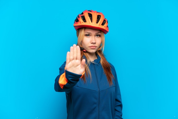 Jovem ciclista isolada em um fundo azul fazendo gesto de pare