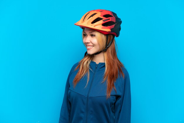 Jovem ciclista isolada em um fundo azul, olhando de lado