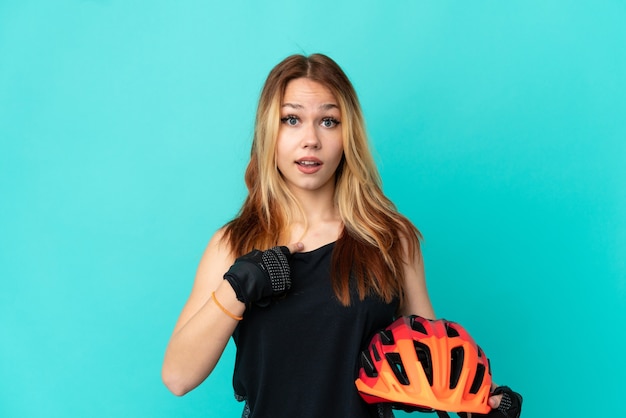 Jovem ciclista sobre fundo azul isolado com expressão facial surpresa