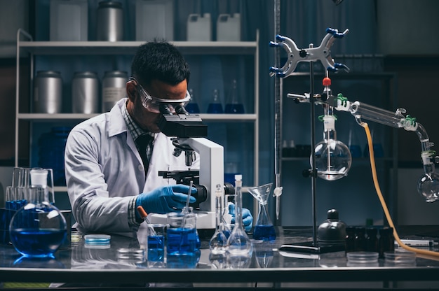 Jovem cientista olhando através de um microscópio em um laboratório. Jovem cientista fazendo alguma pesquisa.