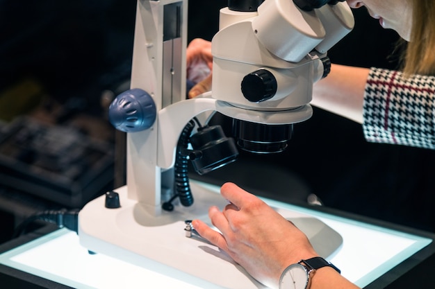 Jovem cientista olhando através de um microscópio em um laboratório.