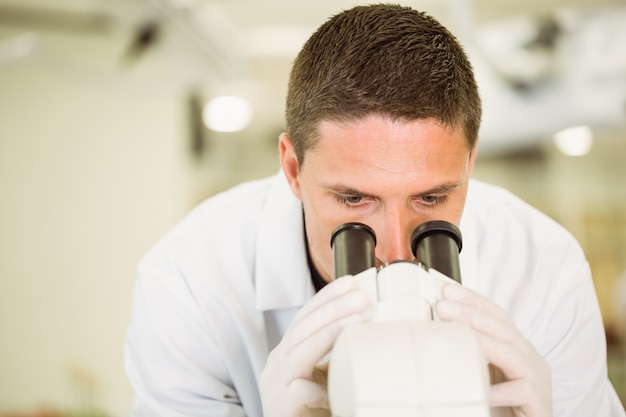 Foto jovem cientista que trabalha com microscópio