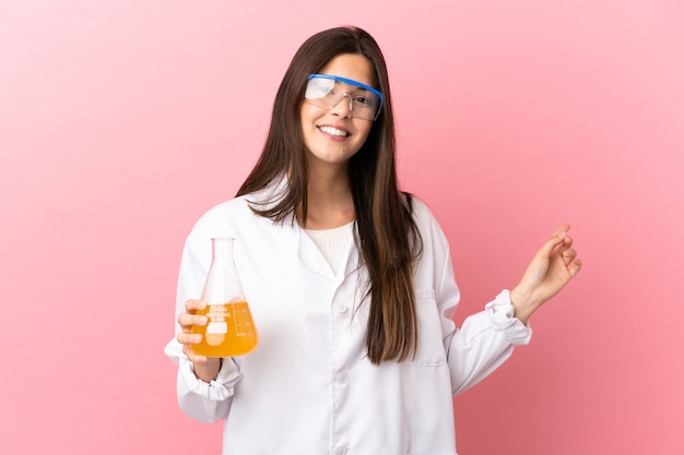 Jovem cientista sobre fundo rosa isolado apontando para trás