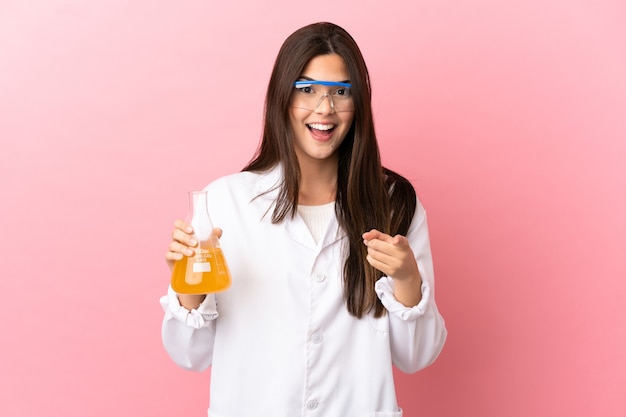 Jovem cientista sobre fundo rosa isolado surpresa e apontando para a frente