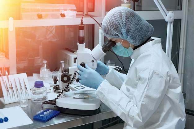 Foto jovem cientista usando microscópio para análise microbiológica no laboratório de ciências médicas
