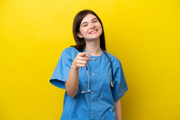 Jovem cirurgiã médica mulher russa isolada em fundo amarelo apontando para a frente com expressão feliz