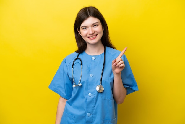 Jovem cirurgiã médica russa isolada em fundo amarelo mostrando e levantando um dedo em sinal do melhor