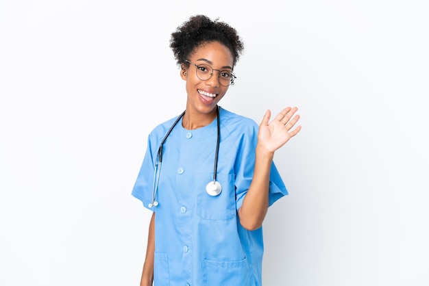 Jovem cirurgiã, médico afro-americano, isolada no fundo branco, saudando com a mão e expressão feliz