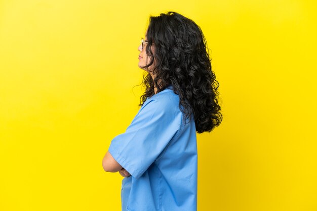 Jovem cirurgiã mulher asiática isolada em fundo amarelo na posição lateral