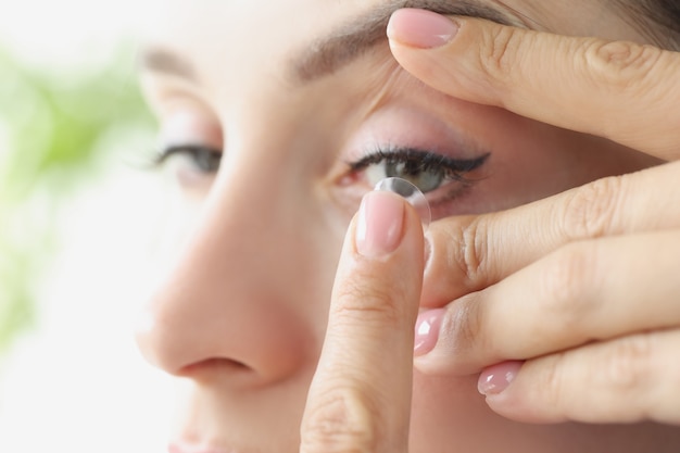 Jovem coloca lentes de contato gelatinosas nos olhos, escolhendo lentes para o conceito de visão