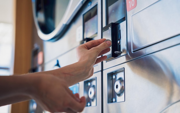 Jovem colocando moedas na máquina de lavar na lavanderia