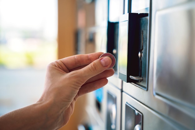 Jovem colocando moedas na máquina de lavar na lavanderia