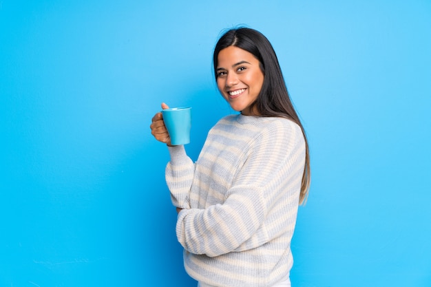 Jovem colombiana com suéter segurando uma xícara de café quente