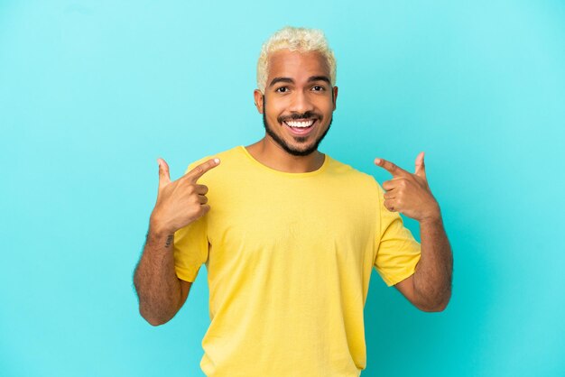 Jovem colombiano bonito isolado em um fundo azul fazendo um gesto de polegar para cima