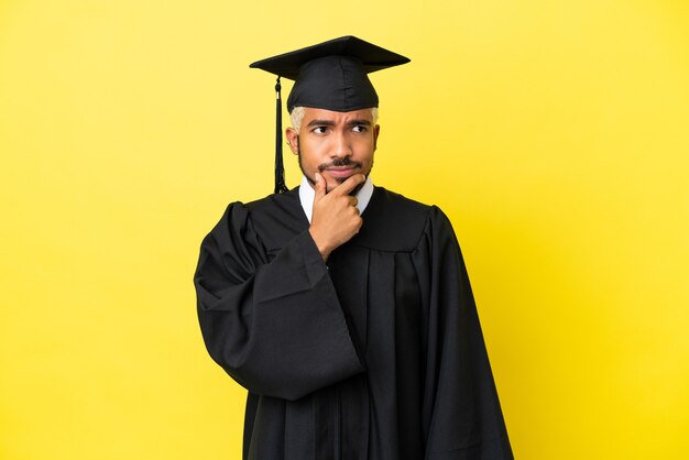 Jovem colombiano graduado pela universidade isolado em um fundo amarelo com dúvidas e expressão facial confusa