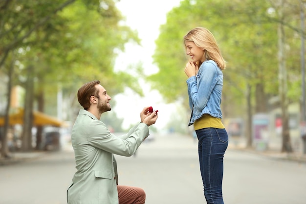 Foto jovem com anel de noivado fazendo proposta para sua amada namorada ao ar livre