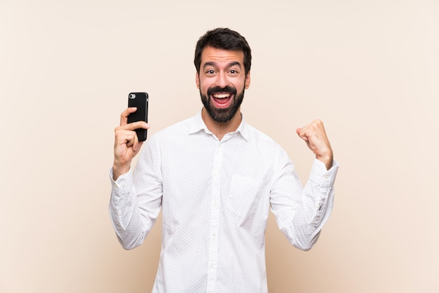 Jovem com barba segurando um celular surpreso e enviando uma mensagem