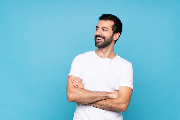 Jovem com barba sobre azul isolado feliz e sorridente