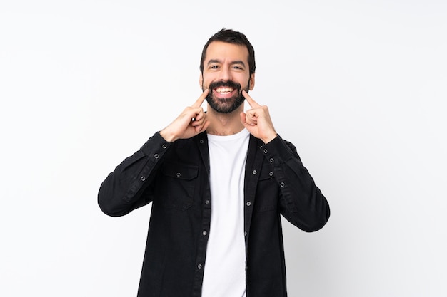 Jovem com barba sobre parede branca isolada, sorrindo com uma expressão feliz e agradável