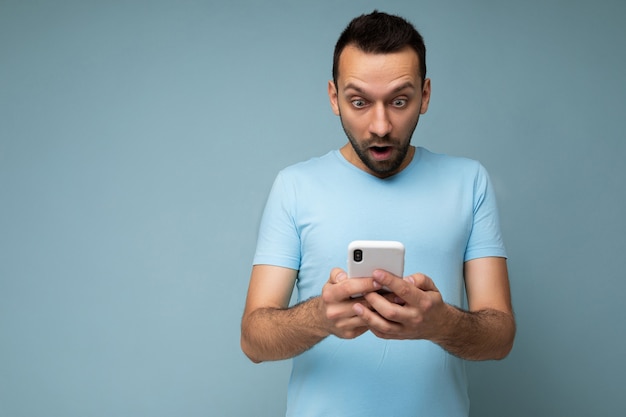 Jovem com barba usando uma camiseta azul comum isolada sobre o azul