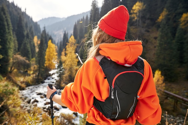 jovem com bastões de trekking andando na trilha de montanha de outono