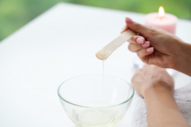 Jovem com belas mãos colocando um pouco de cera sobre eles para remover todo o cabelo