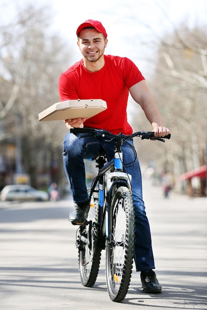 Jovem com bicicleta entregando pizza