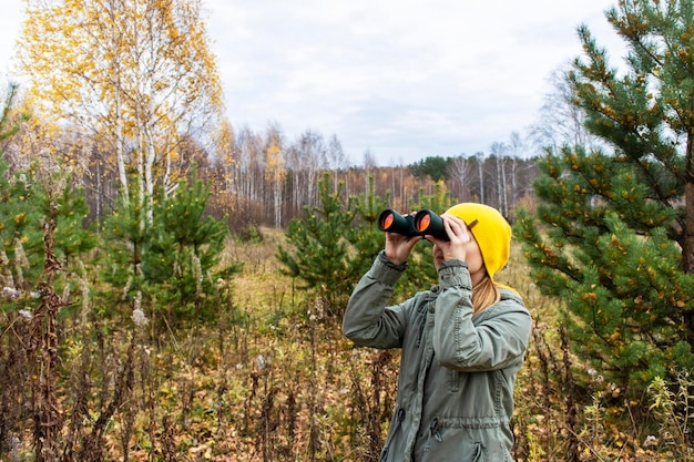 Jovem com binóculos observando pássaros na floresta de outono Pesquisa científica observação de pássaros