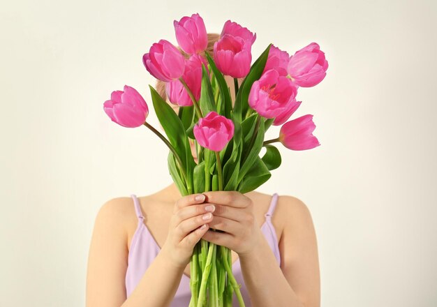 Jovem com buquê de lindas tulipas lilás em fundo branco