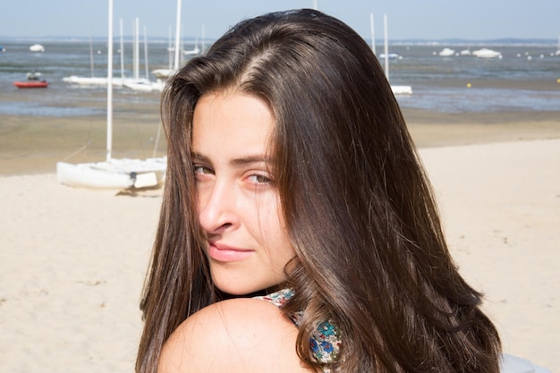 jovem com cabelo comprido está esperando o namorado na beira da praia na areia