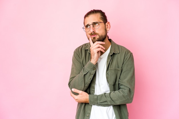 Jovem com cabelo comprido olha contemplando, planejando uma estratégia, pensando no jeito de um negócio.