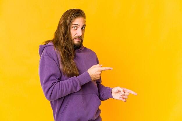 Jovem com cabelo comprido parece chocado apontando com o dedo indicador para um espaço de cópia