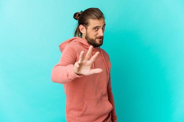 Jovem com cabelo comprido parece rejeitar alguém com um gesto de nojo.