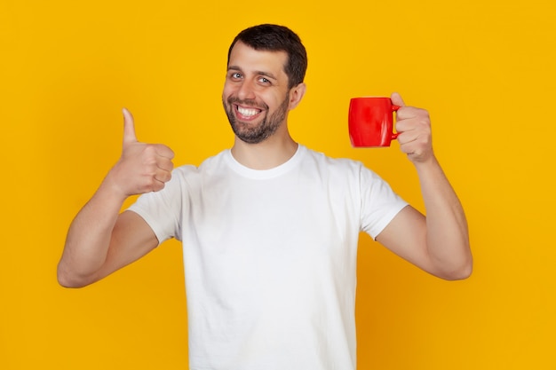 Jovem com caneca de café da manhã na mão mostrando feliz polegar para cima gesto