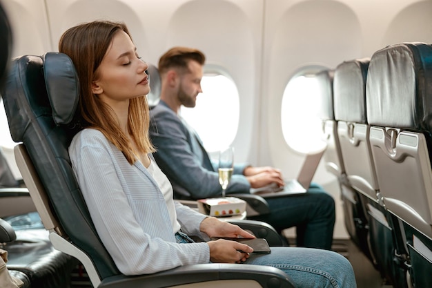 Jovem com celular descansando no avião