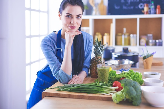 Jovem com cesta de legumes frescos na cozinha