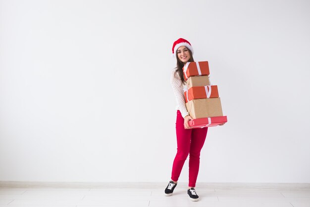 - jovem com chapéu de Papai Noel segurando muitos presentes em um fundo branco com espaço de cópia