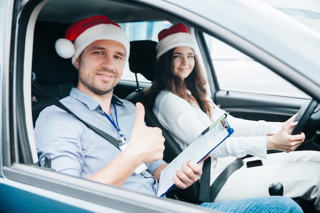 Jovem com chapéu de Papai Noel vermelho dirigindo