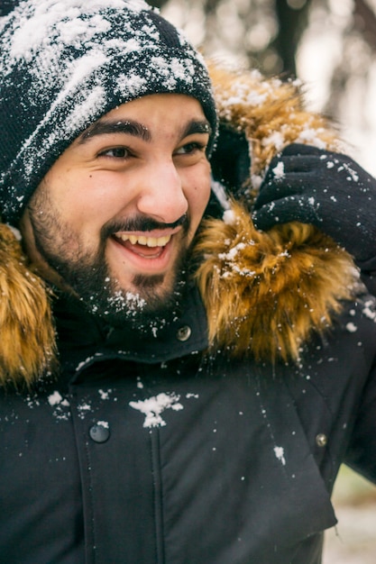 Jovem com chapéu sorrindo na neve