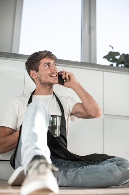 Jovem com copo de água lendo SMS em seu telefone