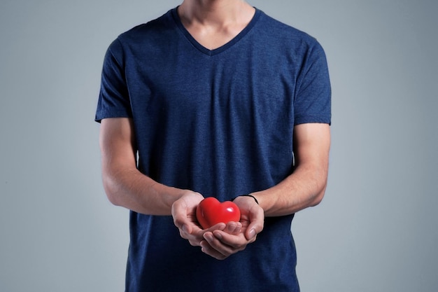 Jovem com coração vermelho sobre fundo cinza